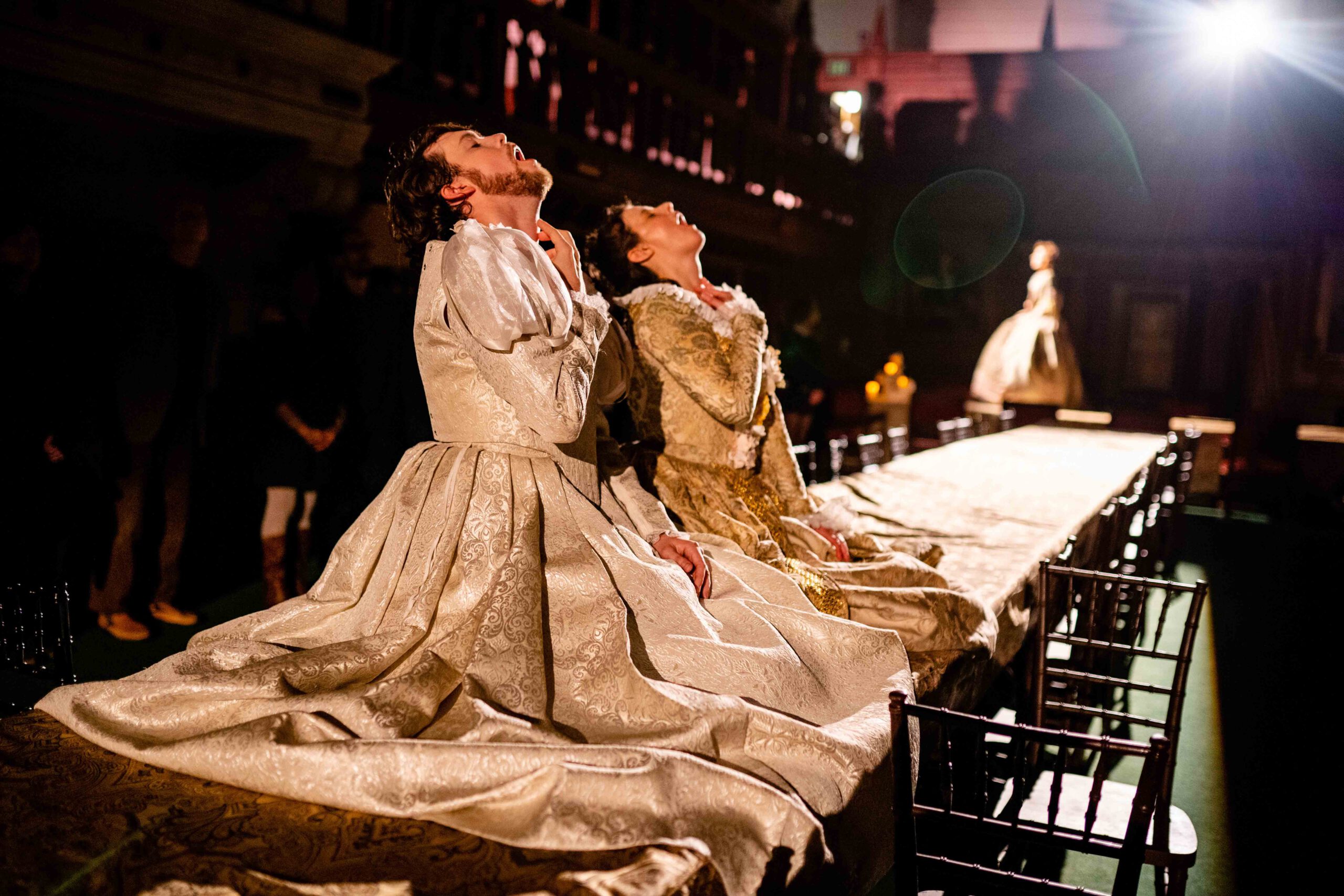 Actors in “Confection” place themselves on the banquet table, asking the audience to consider the intimate connections between food, culture, and the human body.